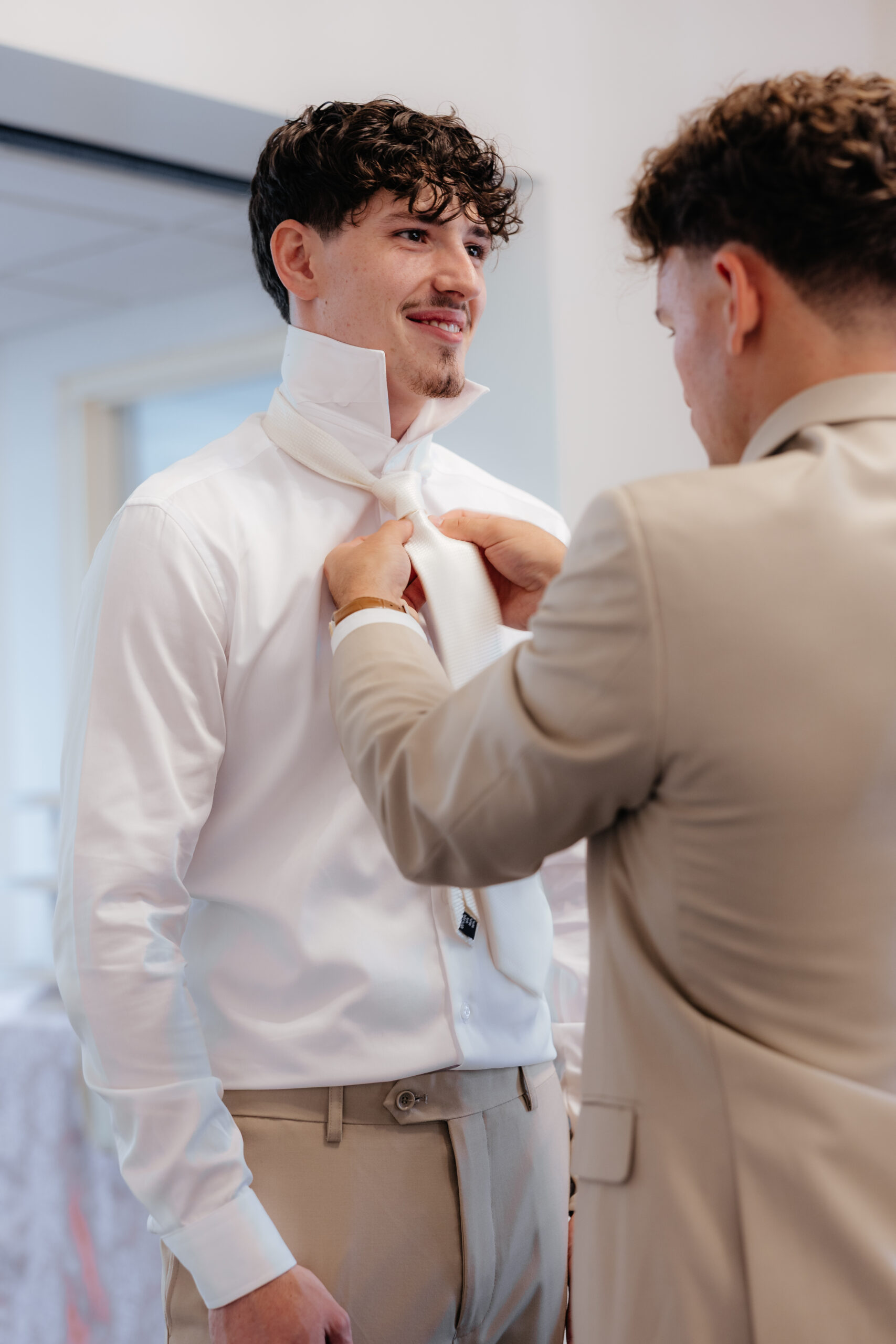 A groomsmen fixing a groom's tie.