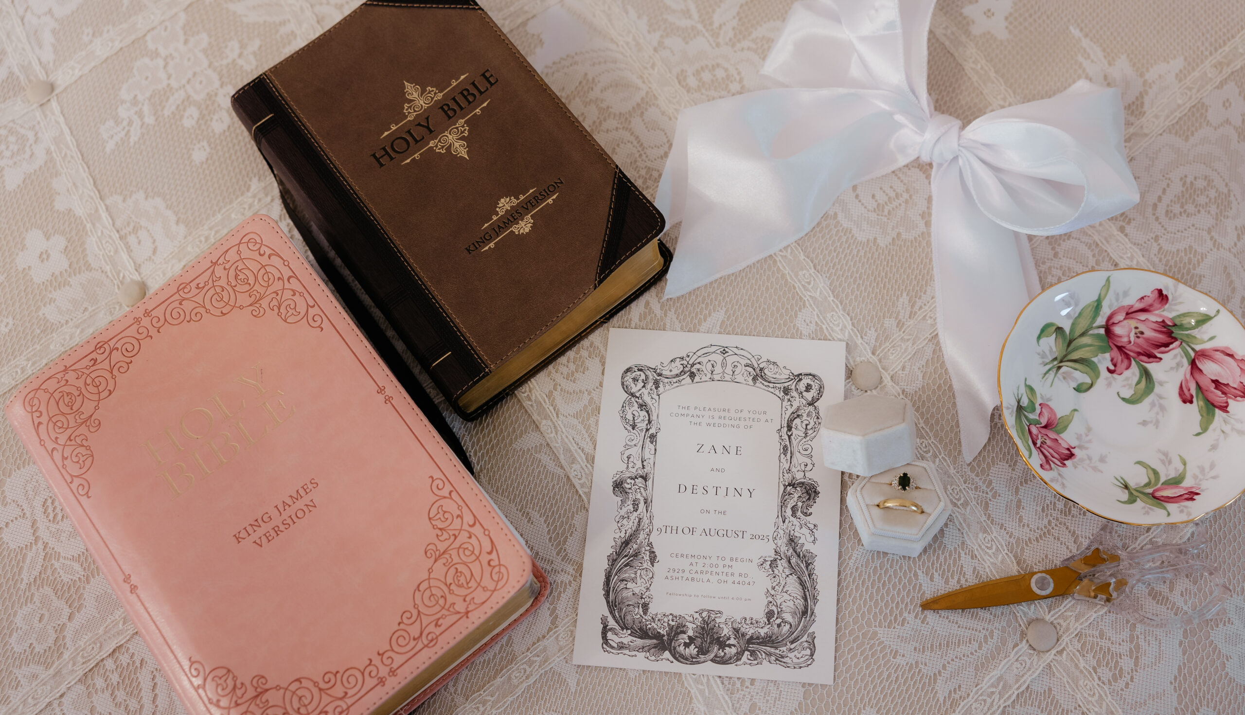 A flat lay of the bride and groom's bibles with a jewelry dish and their wedding invitation.