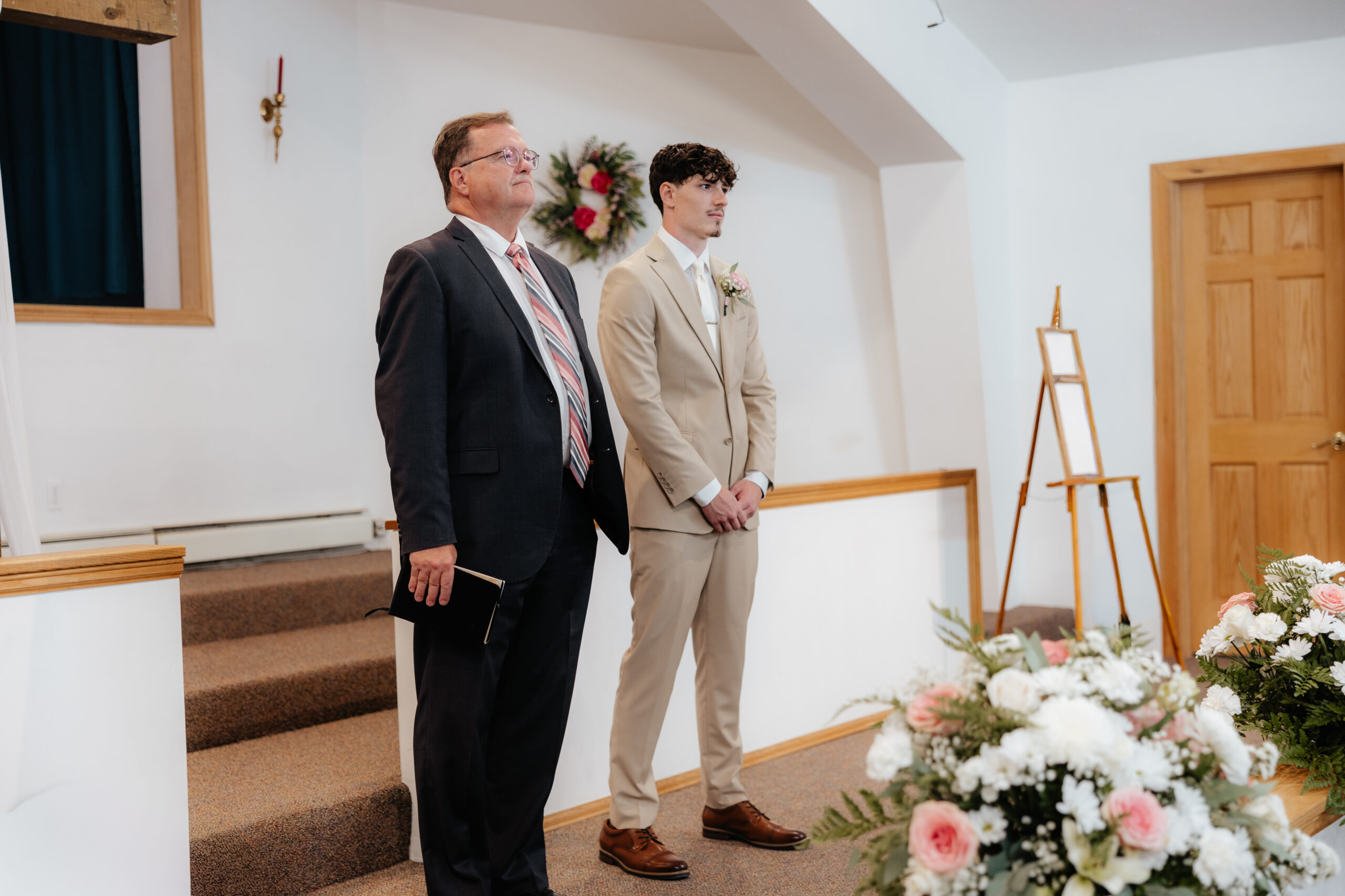 A groom and a pastor looking out to the crowd of people.