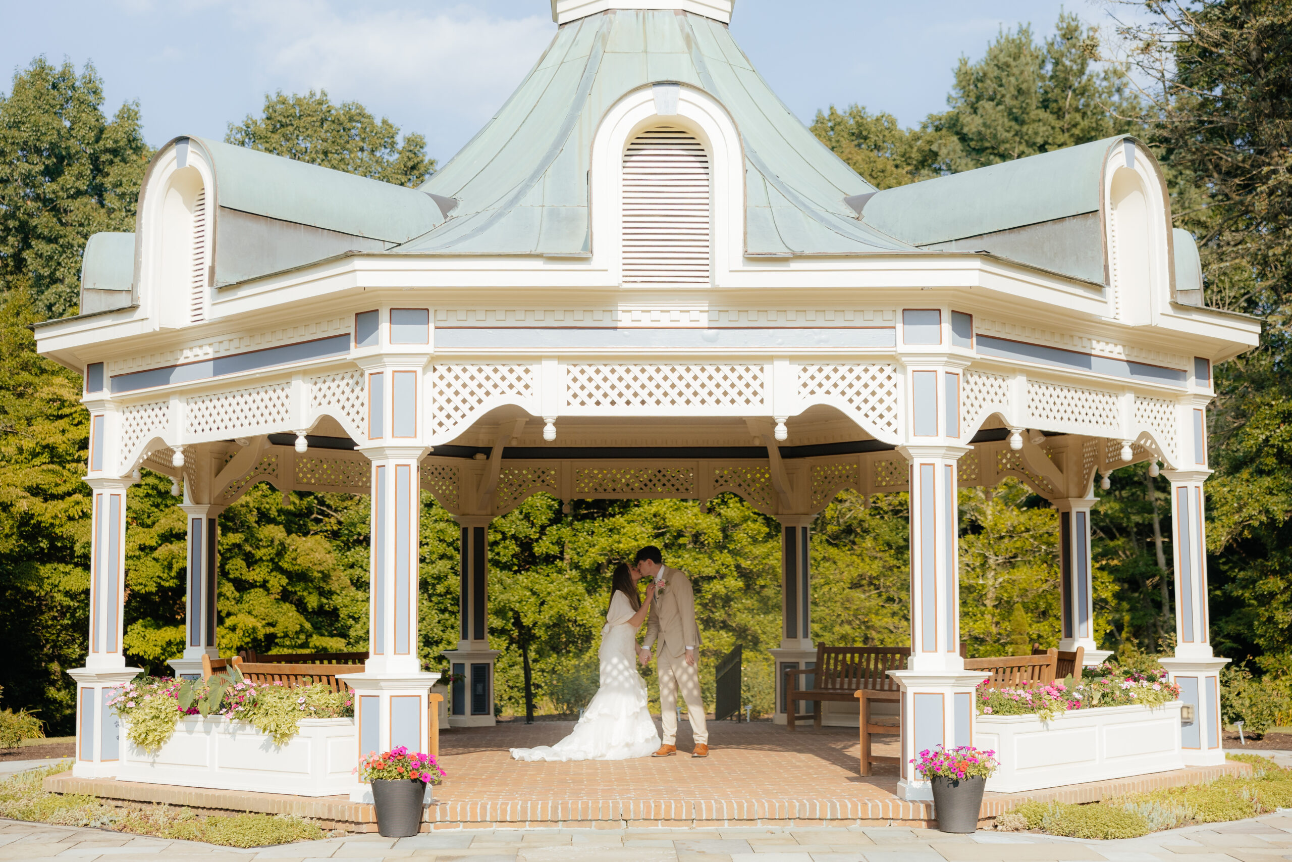 A bride and groom posed together under a gazebo.