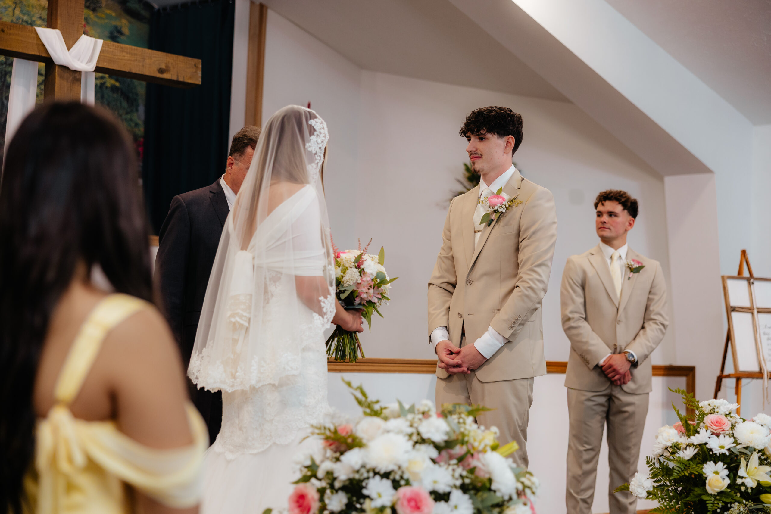 A bride and groom at the alter starring at each other.