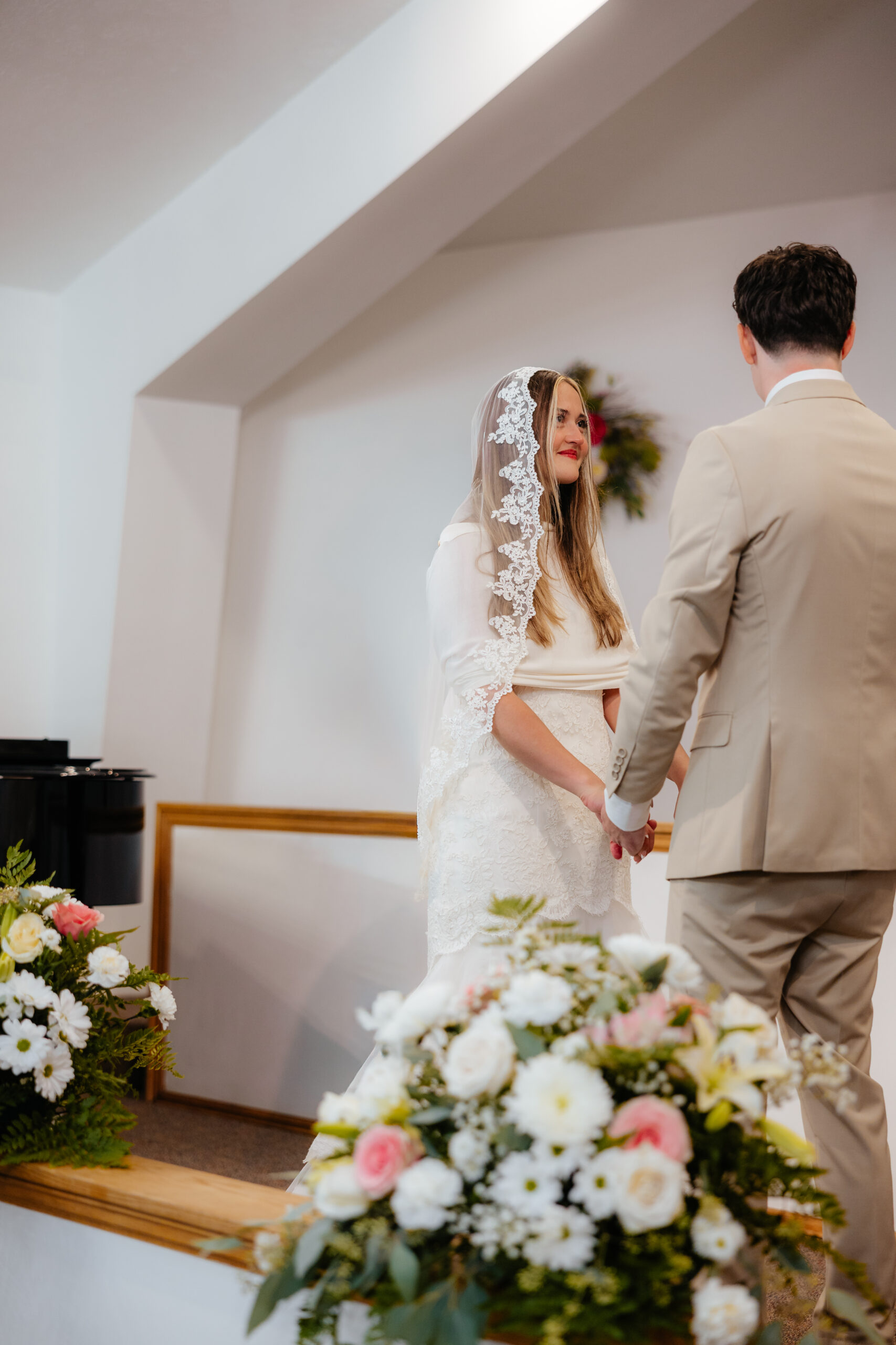 A bride and groom at the alter starring at each other.
