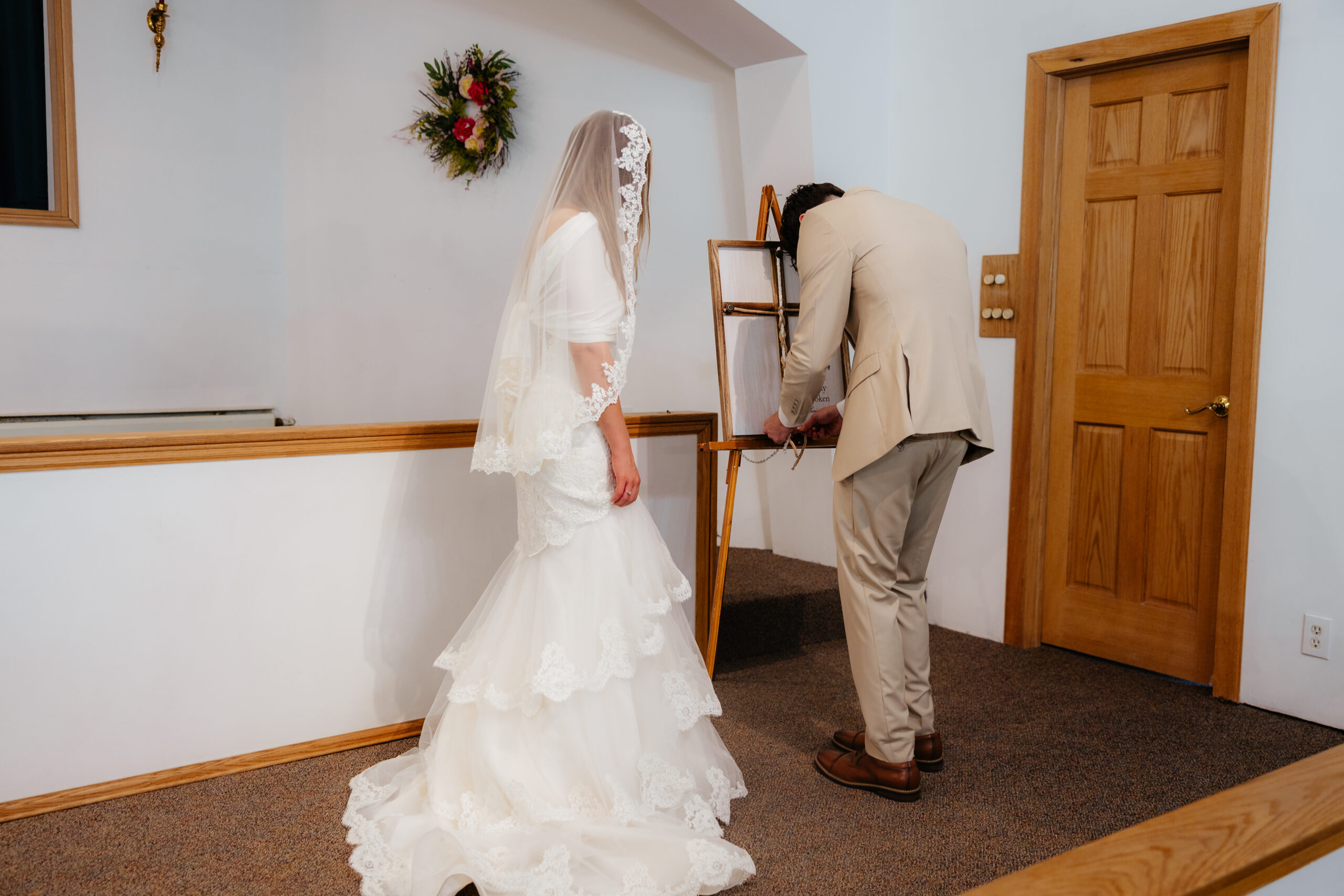 A bride and groom tying a cross with a rope braided as decor at a wedding.