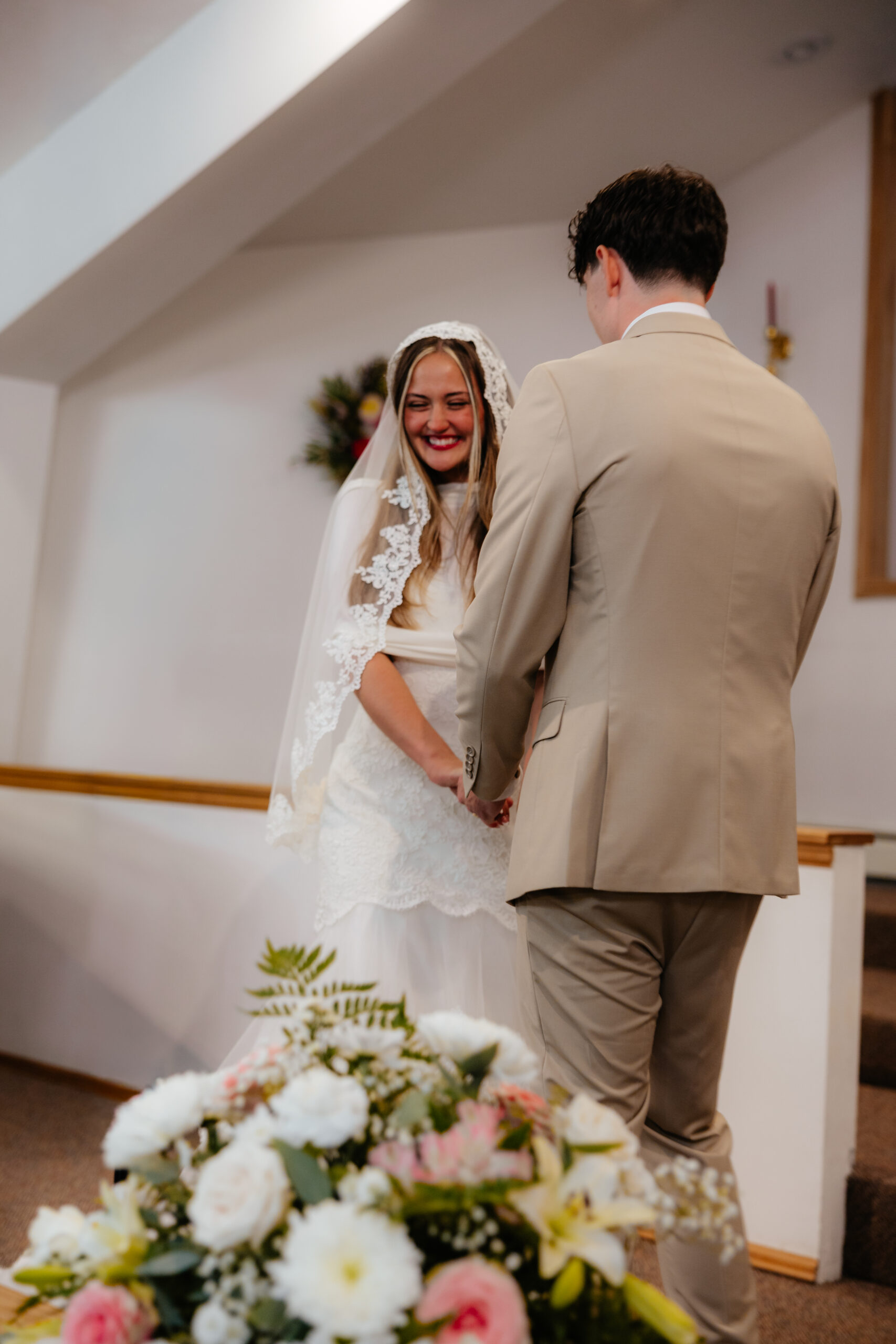 A bride and groom at the alter starring at each other.