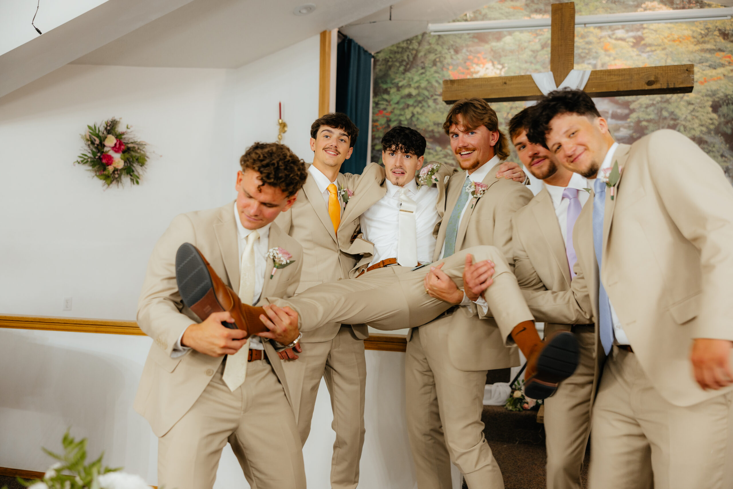 A groom being held by his groomsmen posing.