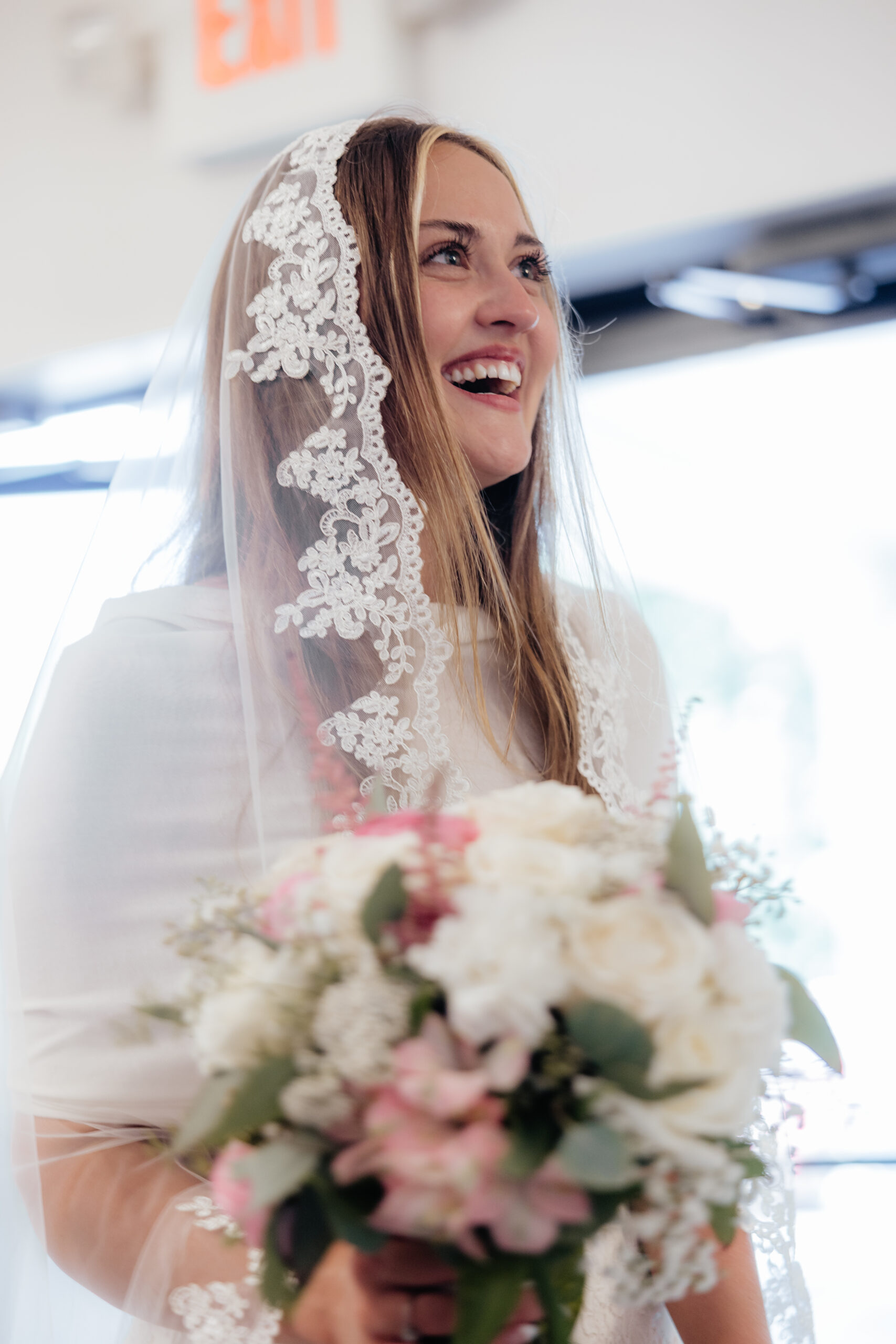 A bride smiling with her bouquet.