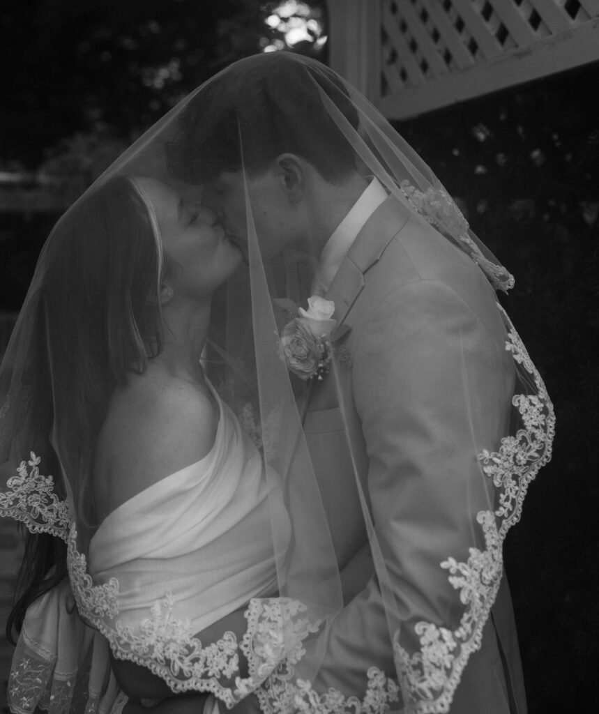 A bride and groom under a veil.
