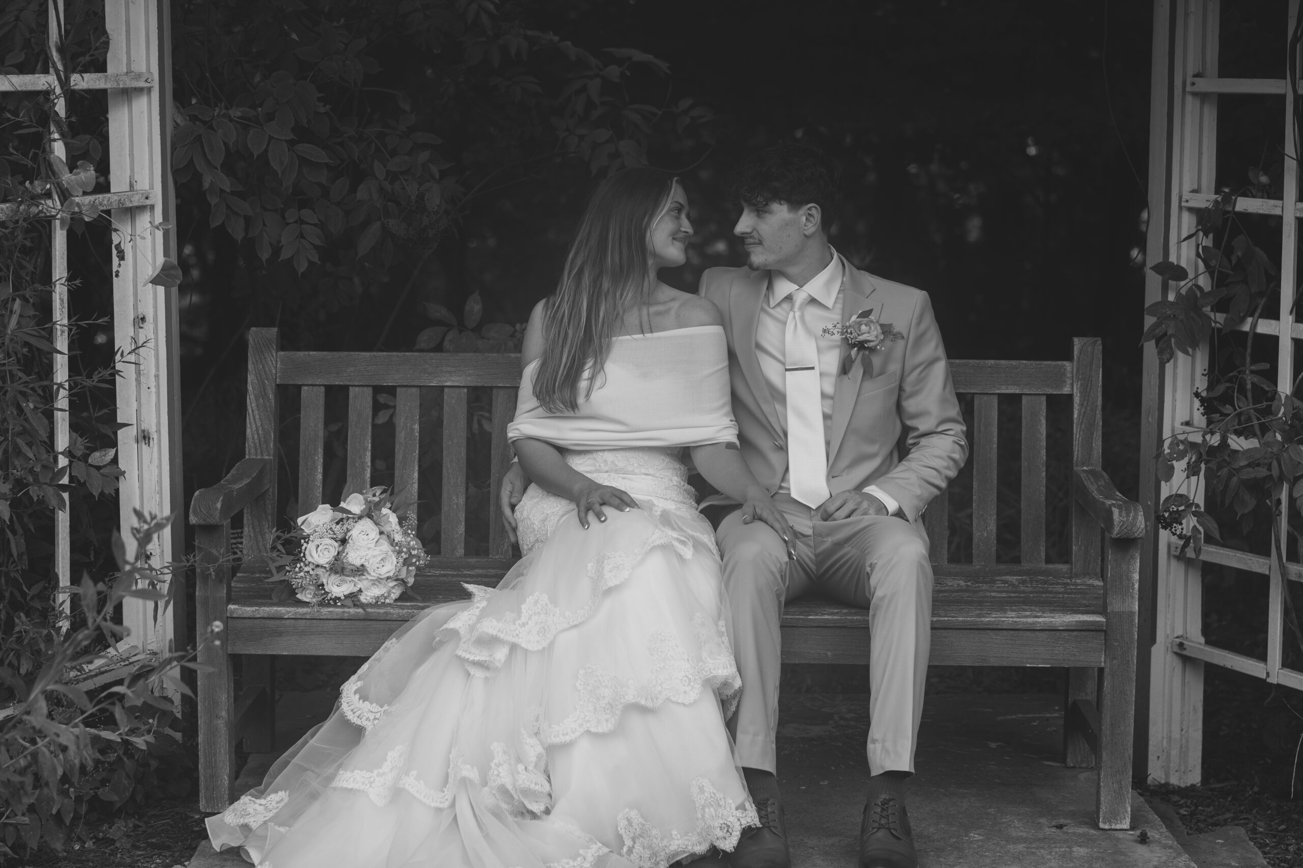 A bride and groom sitting on a bench.