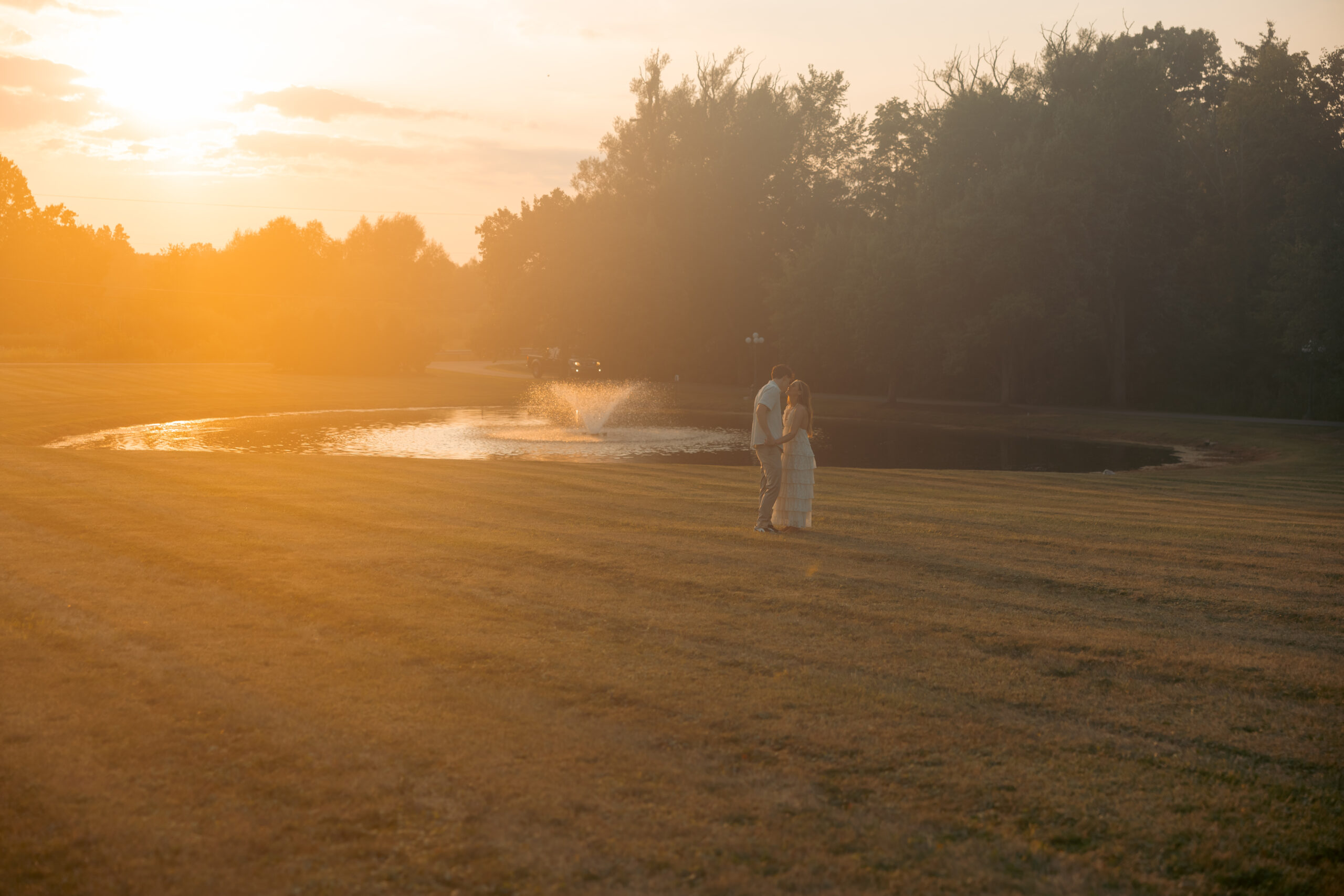 A bride and groom at sunset kissing.