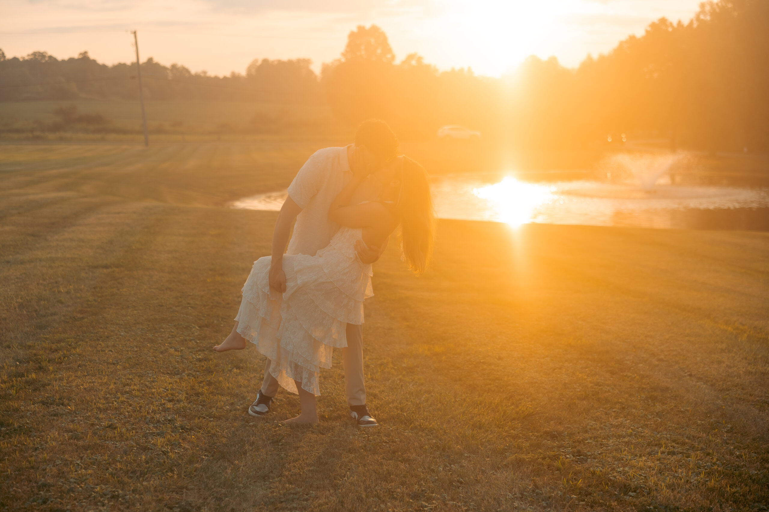 A bride and groom at sunset kissing.