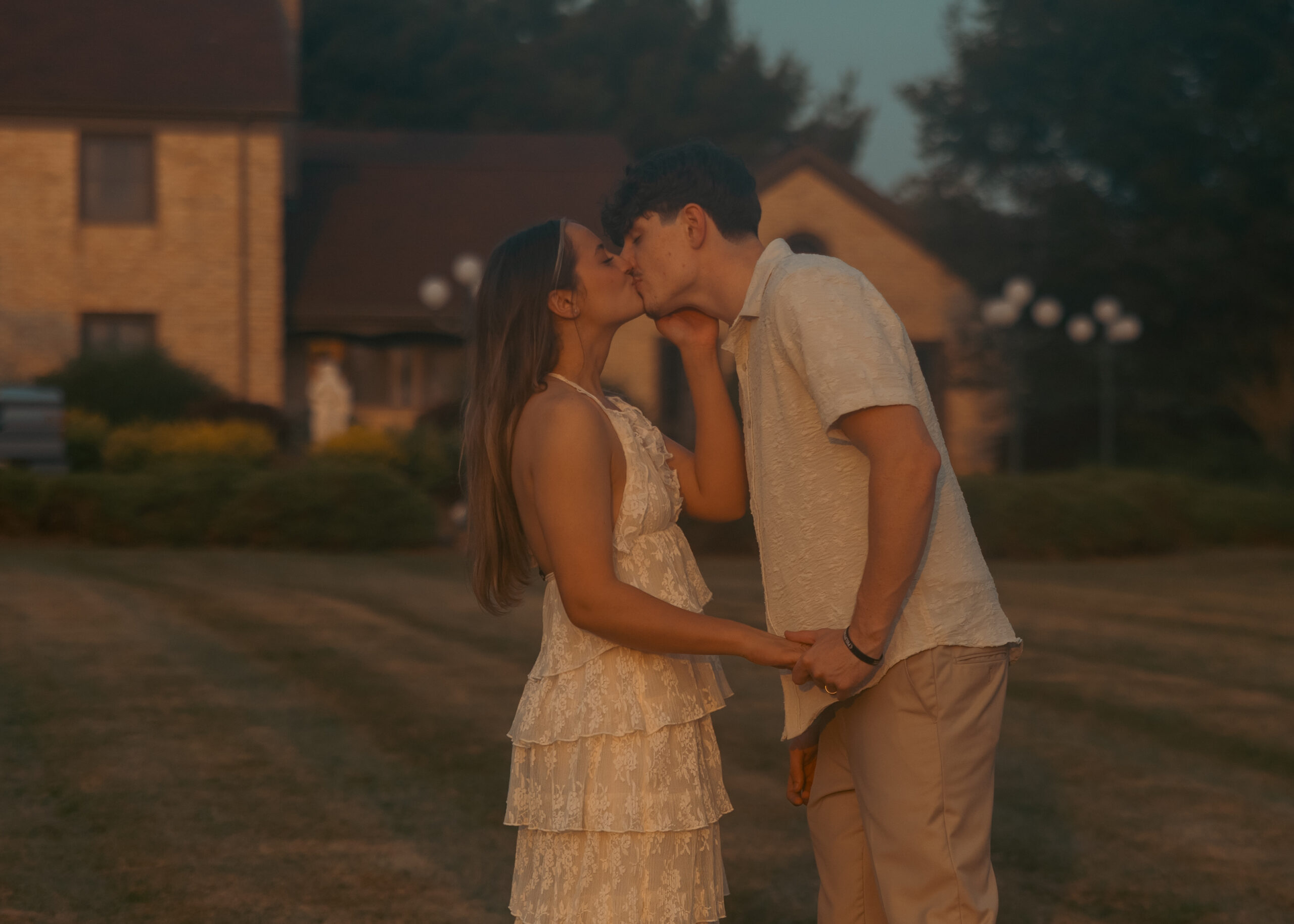 A bride and groom at sunset kissing.
