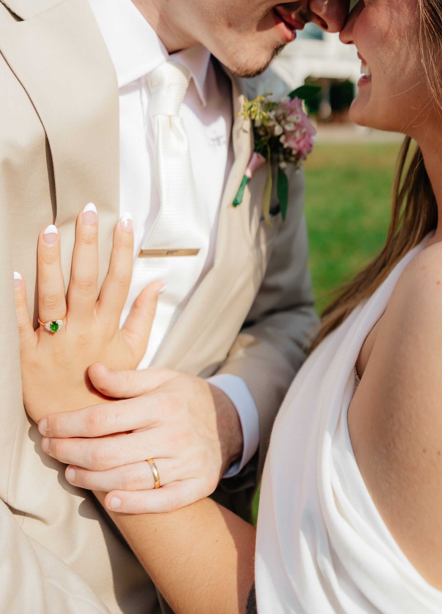 A bride and groom holding hands. touching noses.